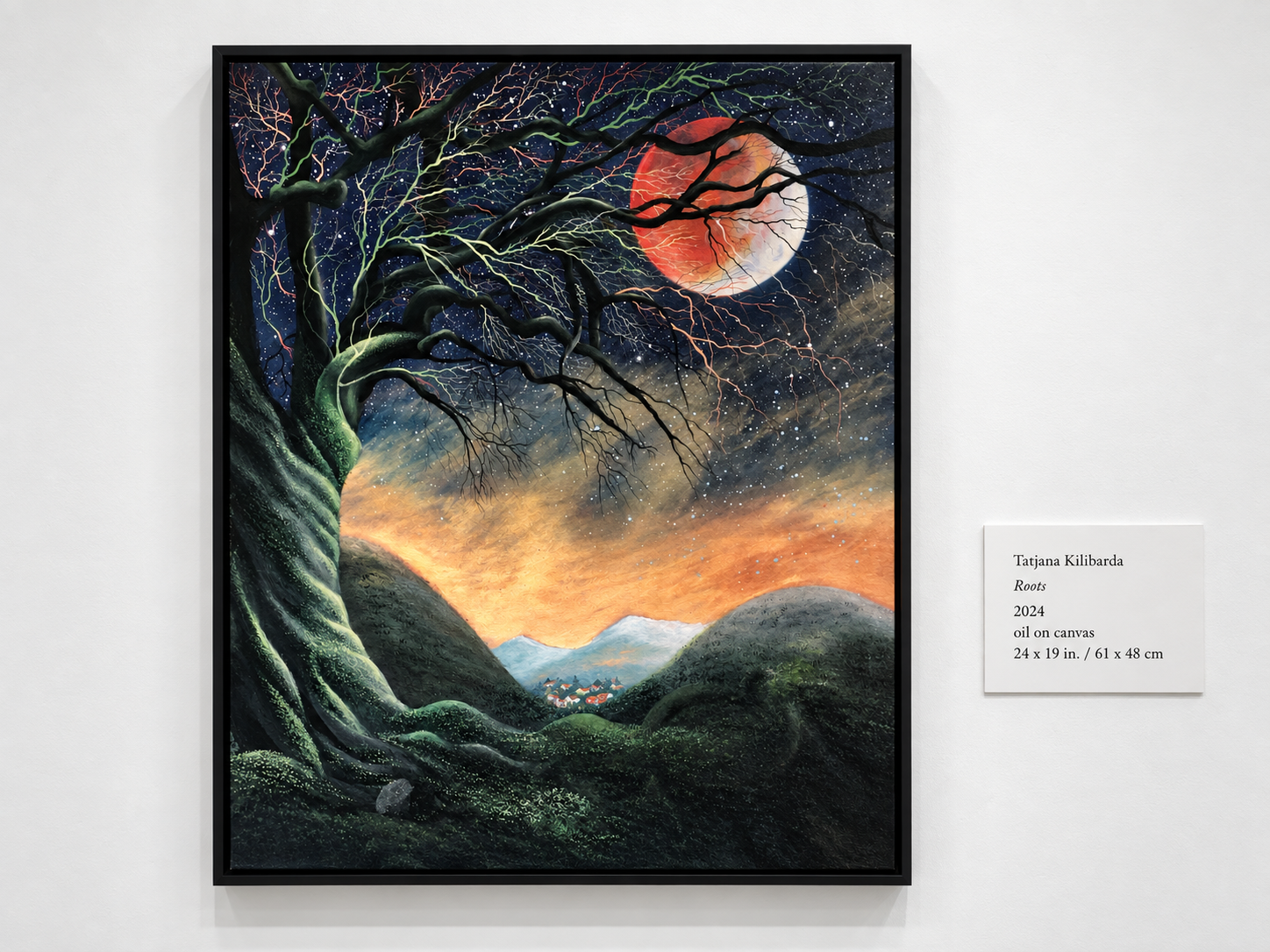 Roots displayed on a gallery wall beside its exhibition label.