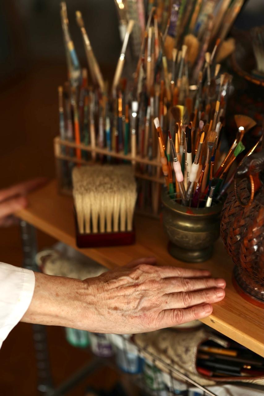 Tatjana Kilibarda’s hand resting beside a collection of paintbrushes in her studio.